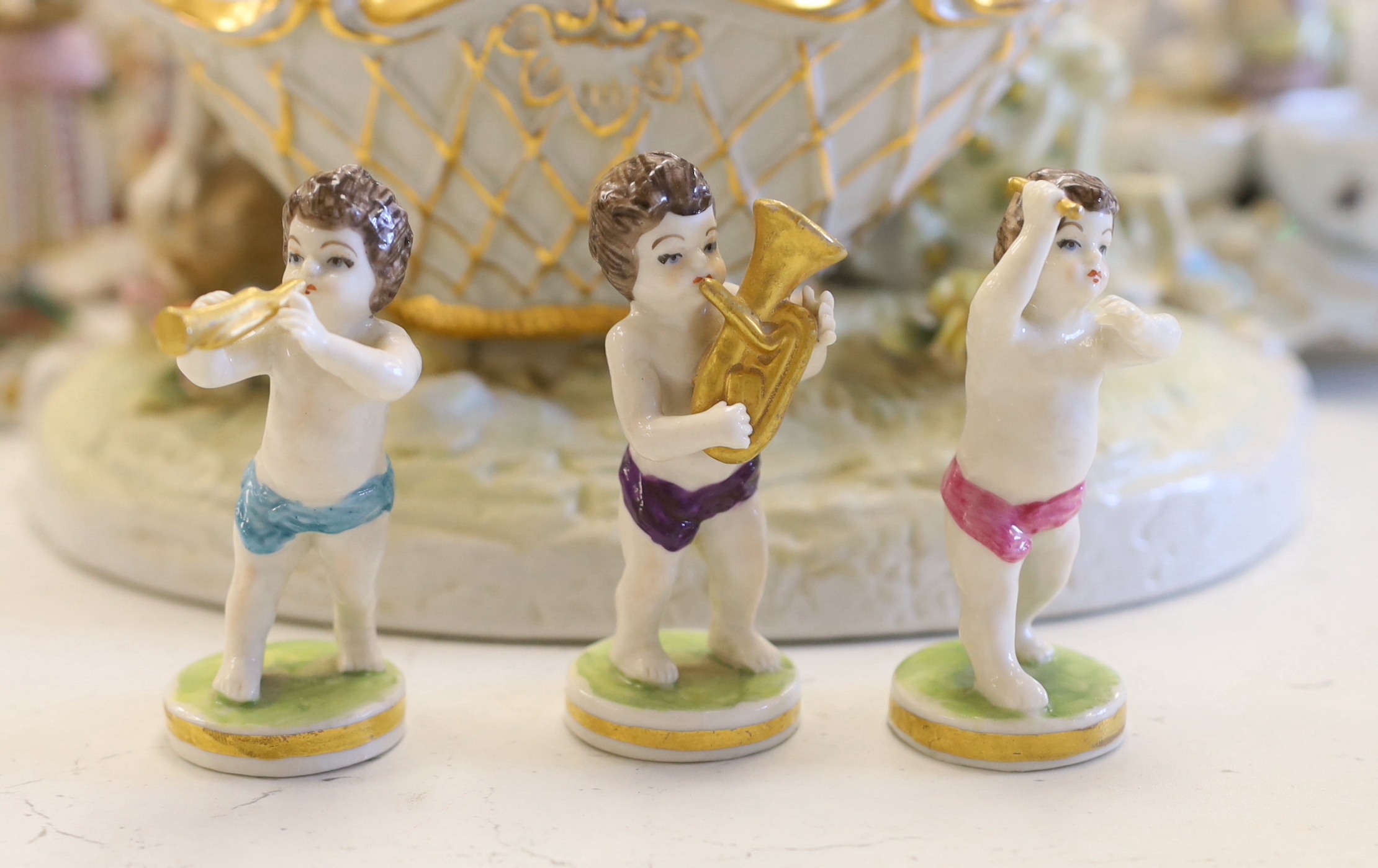 A collection of Continental porcelain figures, candleholders, table centres, some marked ‘AR’, cherubs, lovers, salesmen, tallest 20.5cm (15)